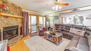 A living room with a stone fireplace, leather sofas, and a ceiling fan. - Community Perks! 'Mtn Serenity Retreat' in Newland (Newland)