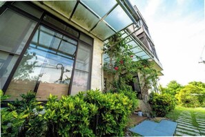 Un edificio moderno con amplios ventanales, un cerramiento de vidrio y abundante vegetación.
