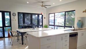 A modern kitchen with a central island, large windows, and a ceiling fan. - Reads Retreat, Black Point (Black Point)