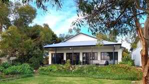 A modern two-story house with a covered porch, surrounded by a well-maintained garden with various plants and flowers. - Reads Retreat, Black Point (Black Point)