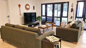 A living room with a sofa, armchair, TV, and a coffee table with books. - Reads Retreat, Black Point (Black Point)