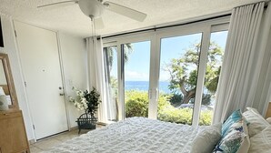 A bedroom with a large bed, a ceiling fan, and a view of the outdoors. - Sea You Soon Retreat+Jeep option (St. Thomas)