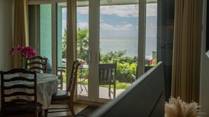 A room with a sliding glass door leading to a balcony with a view of the sea. - Sea You Soon Retreat+Jeep option (St. Thomas)
