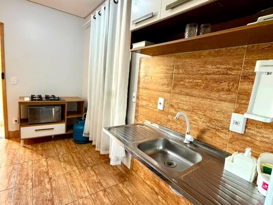 Una cocina moderna con un lavamanos de acero inoxidable, gabinetes de madera y un salpicadero de azulejos.