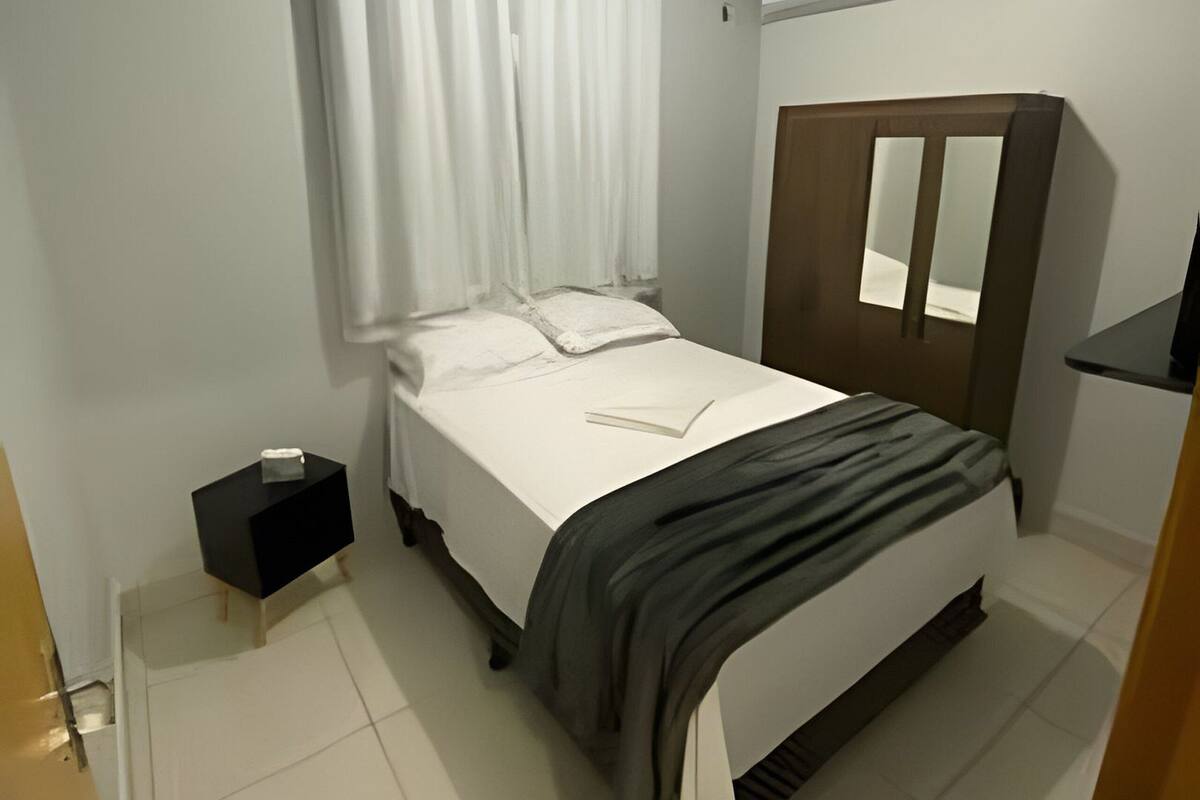 Une chambre à coucher avec un lit, une table de chevet, une armoire et un luminaire au plafond.