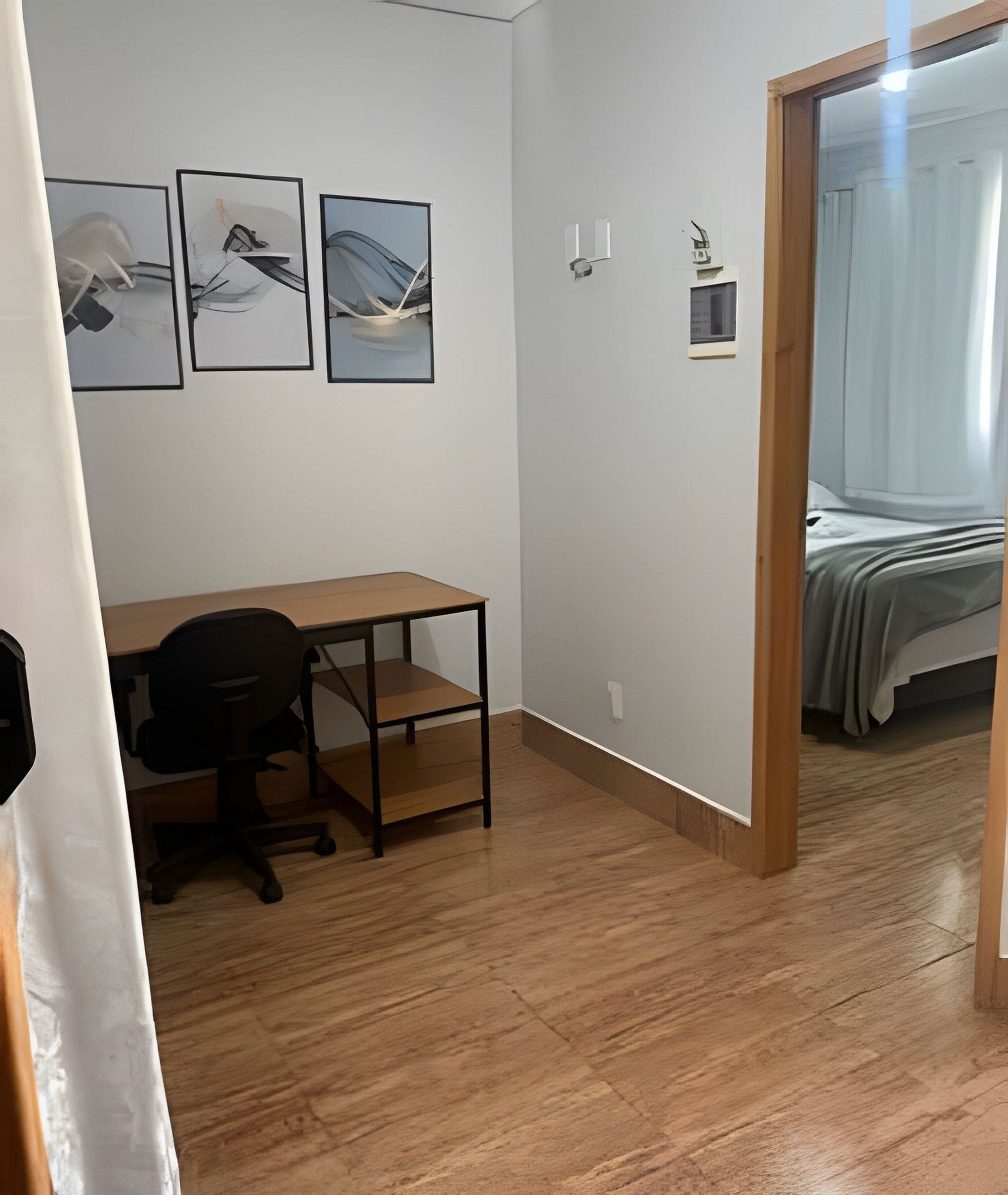 Une pièce avec un bureau en bois, une chaise et trois tableaux encadrés accroch és au mur.