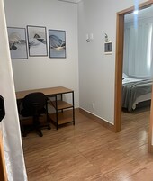 Um quarto com uma escrivaninha de madeira, uma cadeira e três quadros na parede.