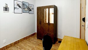 Une pièce avec une table en bois, une chaise noire et un grand meuble en bois. Trois tableaux encadrés sont accrochés au mur.