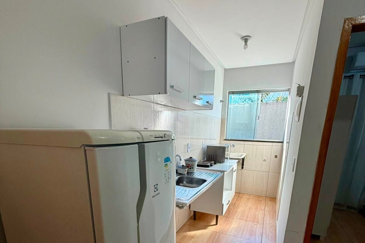 A compact kitchen with a refrigerator, a sink, and cabinets.