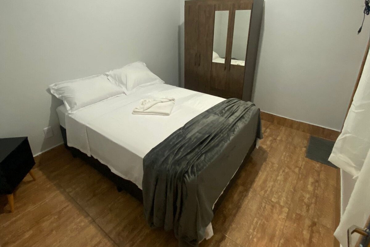 Un dormitorio con una cama, un armario de madera y una lámpara en el techo.