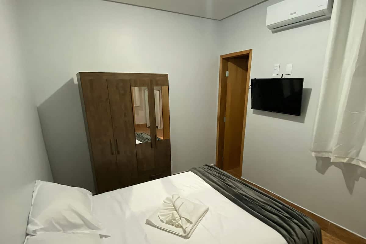 Une chambre à coucher comprenant un lit, une armoire, un téléviseur et un appareil de climatisation.