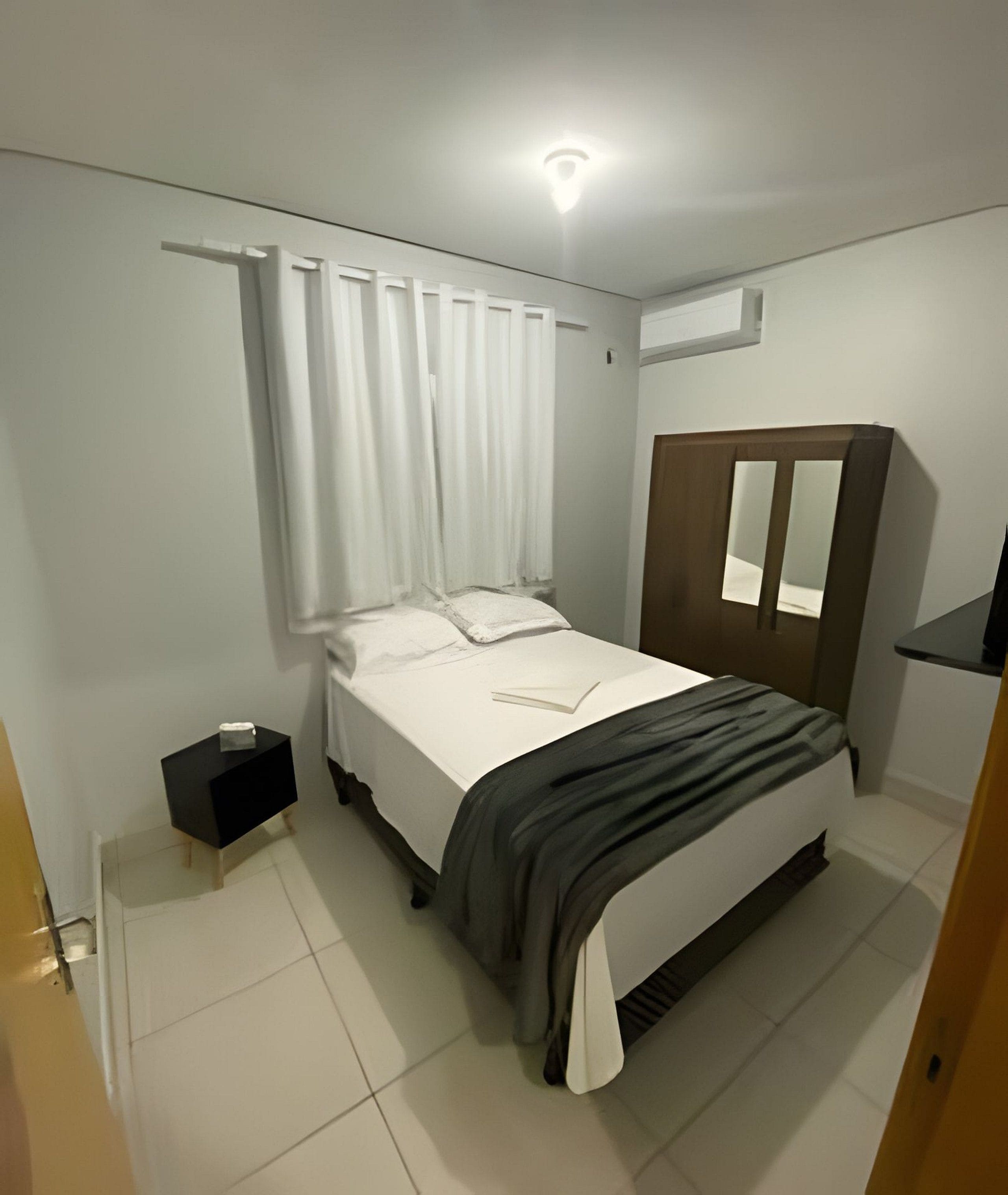 A bedroom with a bed, a bedside table, a wardrobe, and a ceiling light.