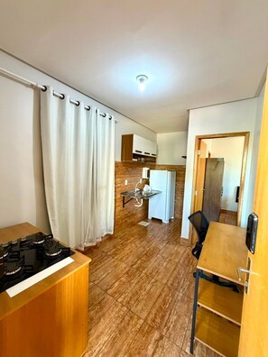 A compact kitchen with a built-in refrigerator, a small countertop, and a dining area with a table and chairs. - EDIFICIO GERVASIO (Goiania)