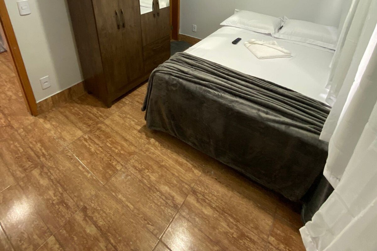 A bedroom with a bed, a wardrobe, and an air conditioning unit.