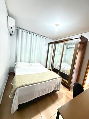 Une chambre d’hôtel équipée d’un lit, d’un bureau, d’une armoire et d’un appareil de climatisation.