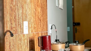 A kitchen with wooden backsplash, stainless steel sink, and two electric kettons on the stove.