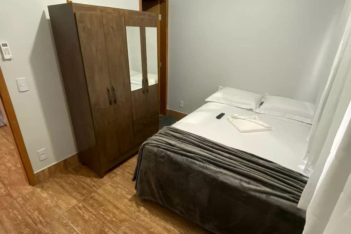 Une chambre à coucher avec un lit, une armoire en bois et un appareil de climatisation.