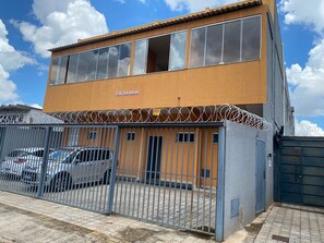 A two-story building with a sign reading "Ed. Cervásio" and a fenced parking area with cars. - EDIFICIO GERVASIO (Goiania)