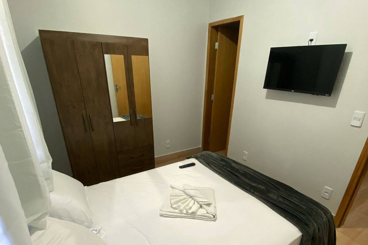 Une chambre à coucher avec un lit, une armoire, un téléviseur et une porte donnant sur la salle de bain.