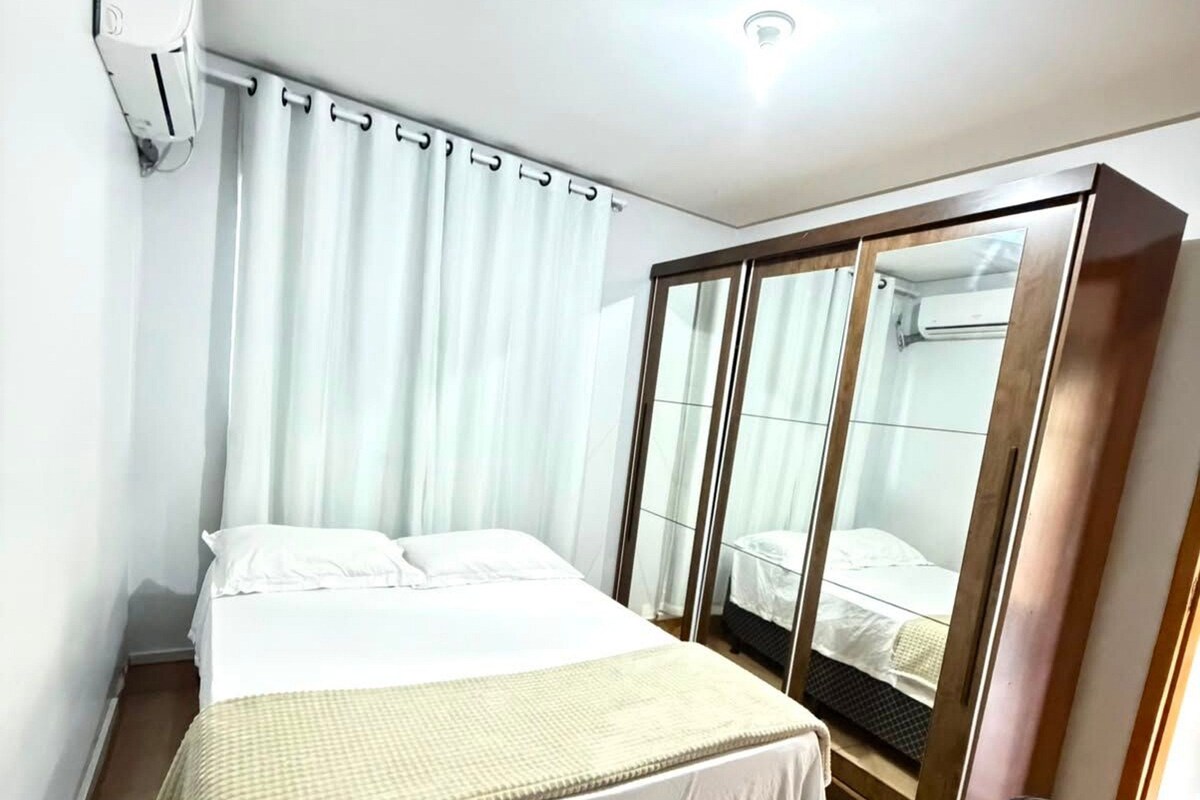 Una habitación de hotel con cama, escritorio, armario y aire acondicionado.
