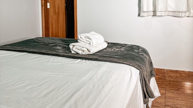 Une chambre à coucher comprenant un lit, un téléviseur fixé au mur, un appareil de climatisation et une porte.