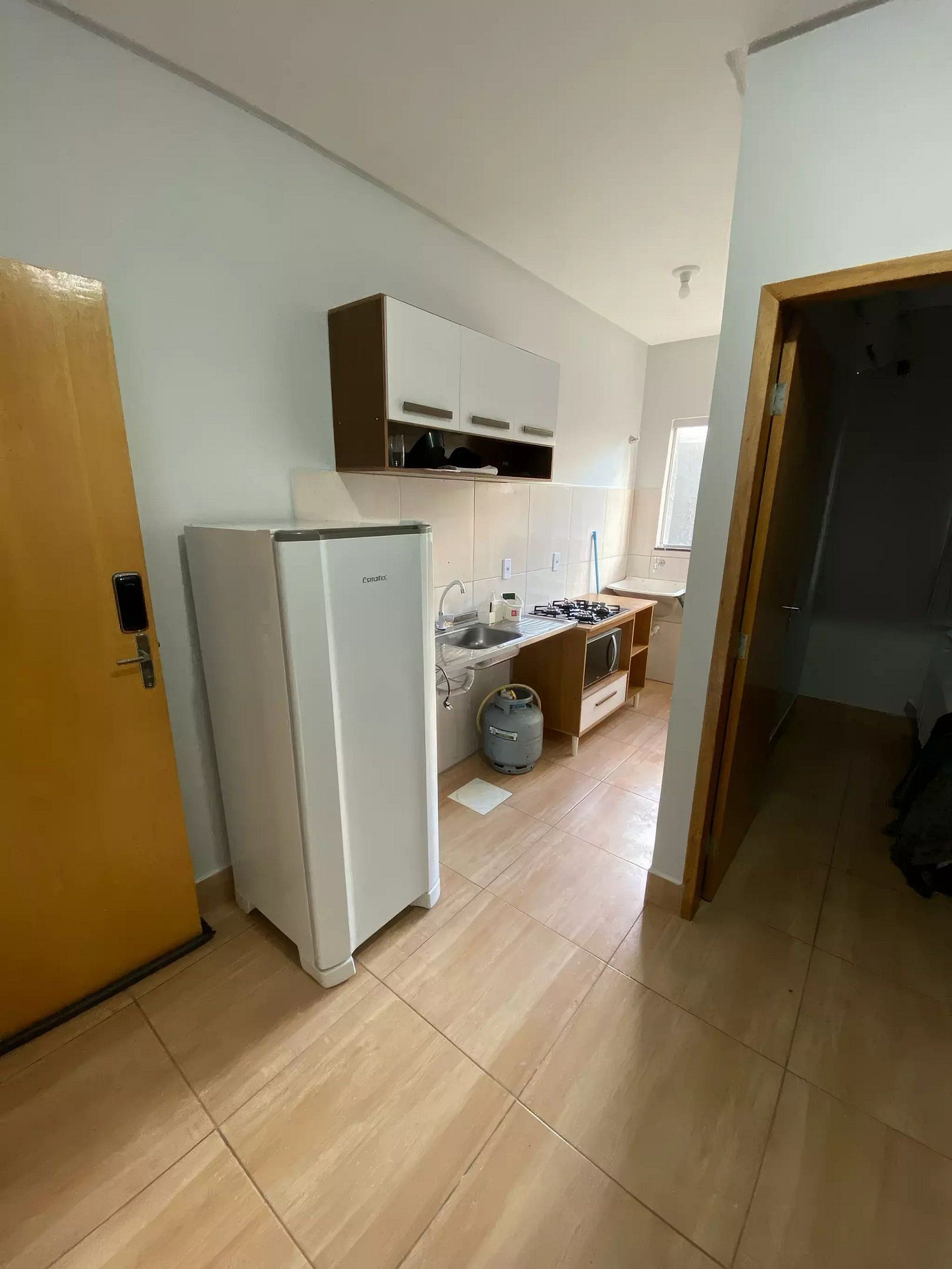 Una cocina con refrigerador, estufa a gas y alacenas.
