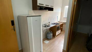 Una cocina con refrigerador, estufa a gas y alacenas.