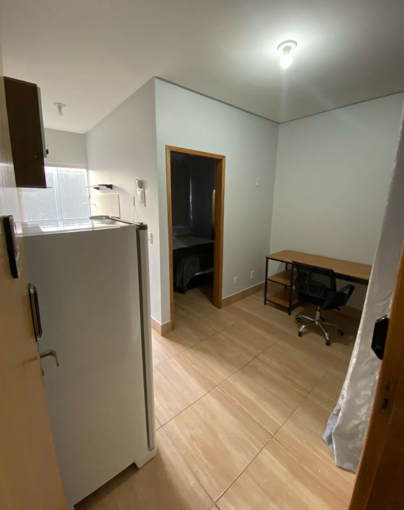 Une cuisine de taille réduite comprenant un réfrigérateur, une petite table à manger et une chaise.