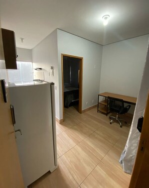 A compact kitchen with a refrigerator, a small dining table, and a chair. - EDIFICIO GERVASIO (Goiania)