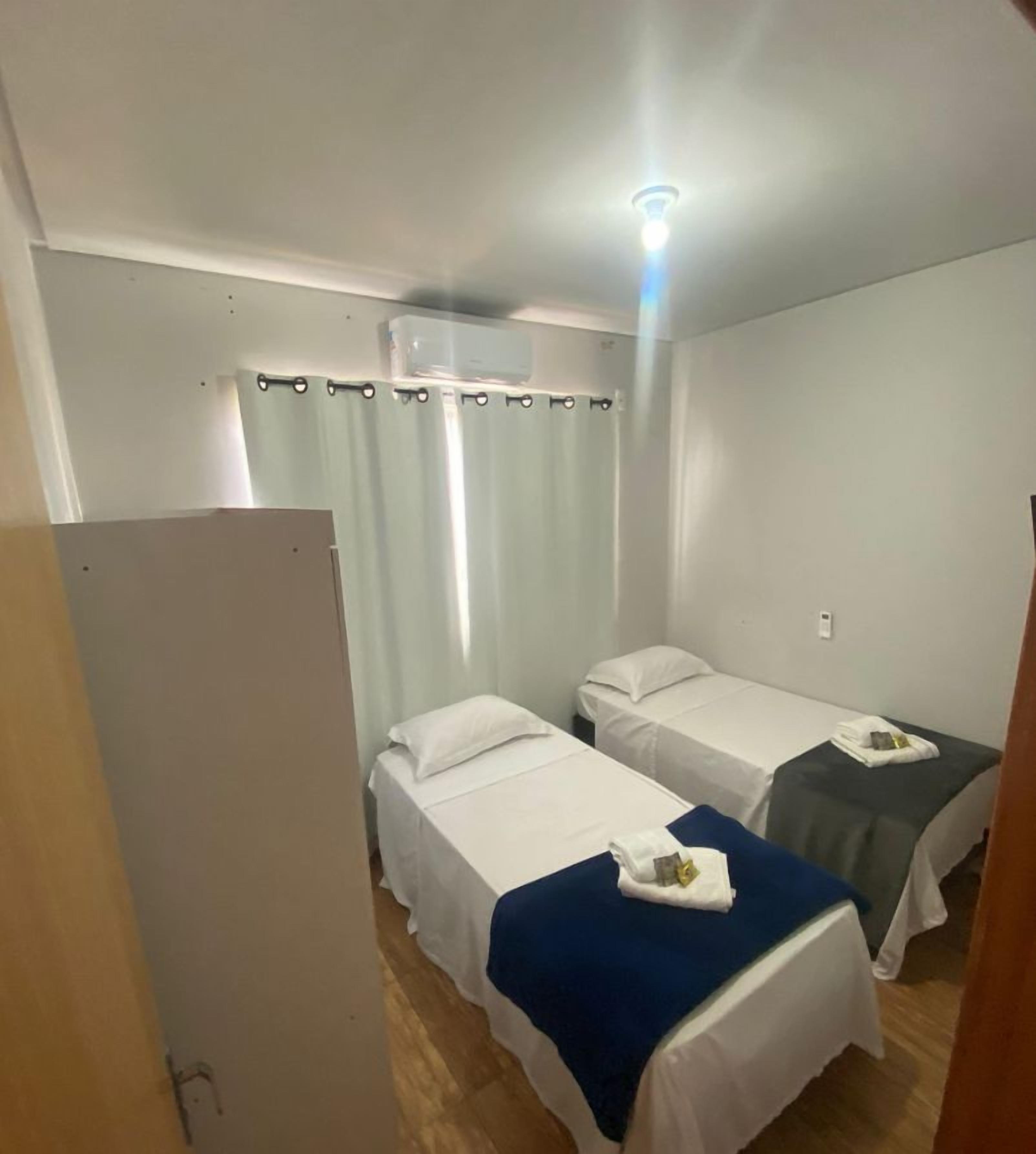 A room with two single beds, a ceiling fan, and a window with curtains.