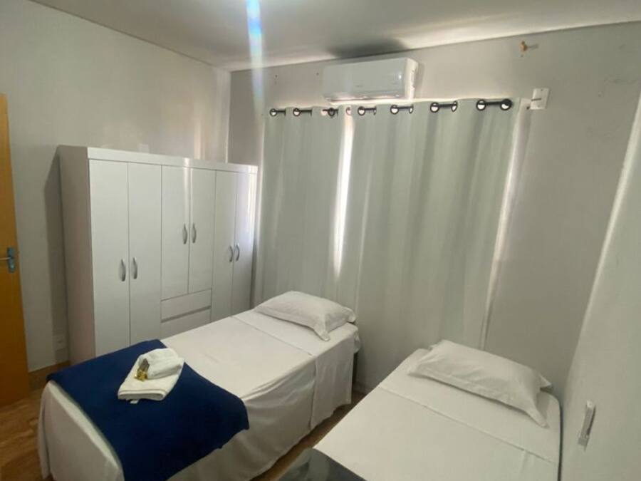 Een kamer met twee eenpersoonsbedden, een kledingkast, een tafel en een plafondlamp.