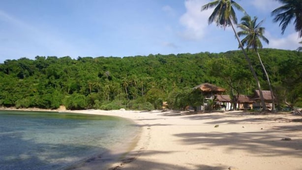 A beach with clear water, sandy shore, and a forested hill in the background. - RedDoorz @ Bansud Oriental Mindoro (Bansud)