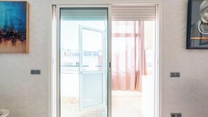 Una habitación con puerta corrediza de vidrio que da a un espacio exterior, una pequeña mesa redonda y un cuadro en la pared.