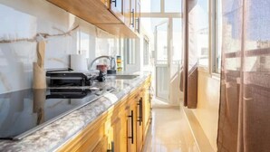 Una cocina moderna con encimera de mármol, armarios de madera y vistas al exterior a través de amplias ventanas.