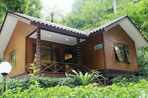 A wooden cabin with a porch, surrounded by lush greenery. - Safari Resort (Cisarua)