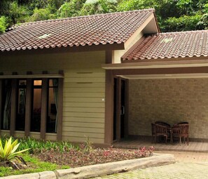 A house with a tiled roof, a covered porch, and a small garden area. - Safari Lodge Hotel (Cisarua)