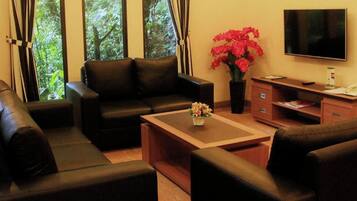 A living room with a sofa set, a coffee table, a TV, and a desk with a chair.