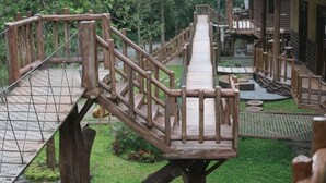 A wooden bridge connecting two areas of a property with a small deck and railing. - Safari Resort (Cisarua)