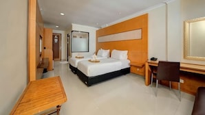 A hotel room with a bed, desk, chair, and a small table. - Safari Resort (Cisarua)