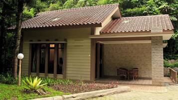 A small building with a tiled roof, a covered entrance, and a patio area with chairs.