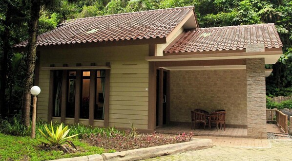 A small building with a tiled roof, a covered entrance, and a patio area with chairs. - Safari Lodge Hotel (Cisarua)
