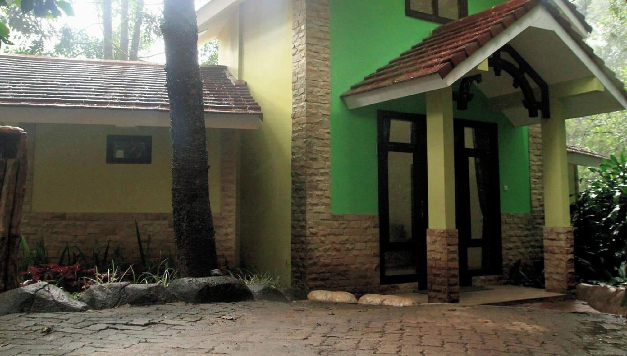 A house with a tiled roof, a green wall, and a stone base.