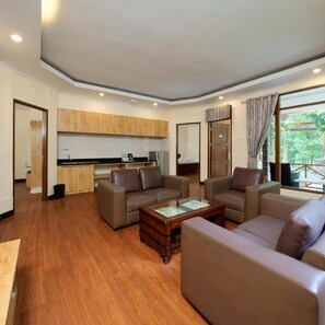 A spacious living area with leather sofas, a coffee table, and a kitchen in the background. - Safari Lodge Hotel (Cisarua)