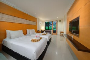 Une chambre d’hôtel avec deux lits, une télévision et une vue sur la verdure environnante.