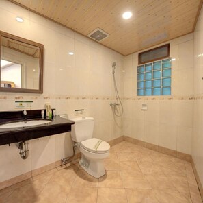 Une salle de bain équipée d’un lavabo, de toilettes, d’une douche et d’une fenêtre avec du verre teinté en bleu.