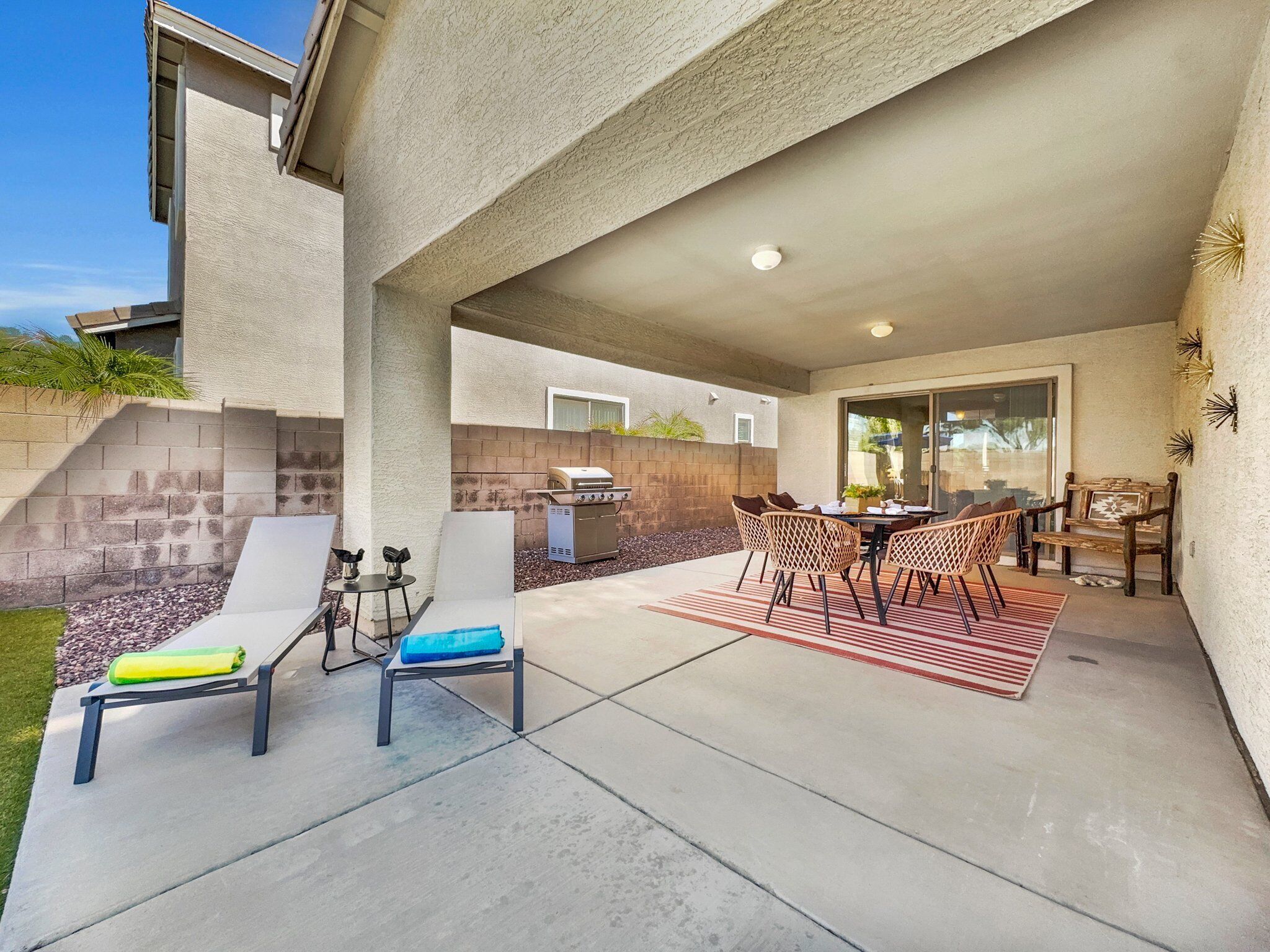 Un patio exterior con una parrilla, zona de estar y vistas de la casa.