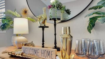 Decoración del hogar con un cartel que dice 'WELCOME HOME', una lámpara, una escultura decorativa de un pájaro, una planta suculenta y una botella sobre una superficie de madera.