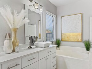 A modern bathroom with a white vanity, a large mirror, a white sink, and a bathtub. - Azurite Queen Creek (Queen Creek)