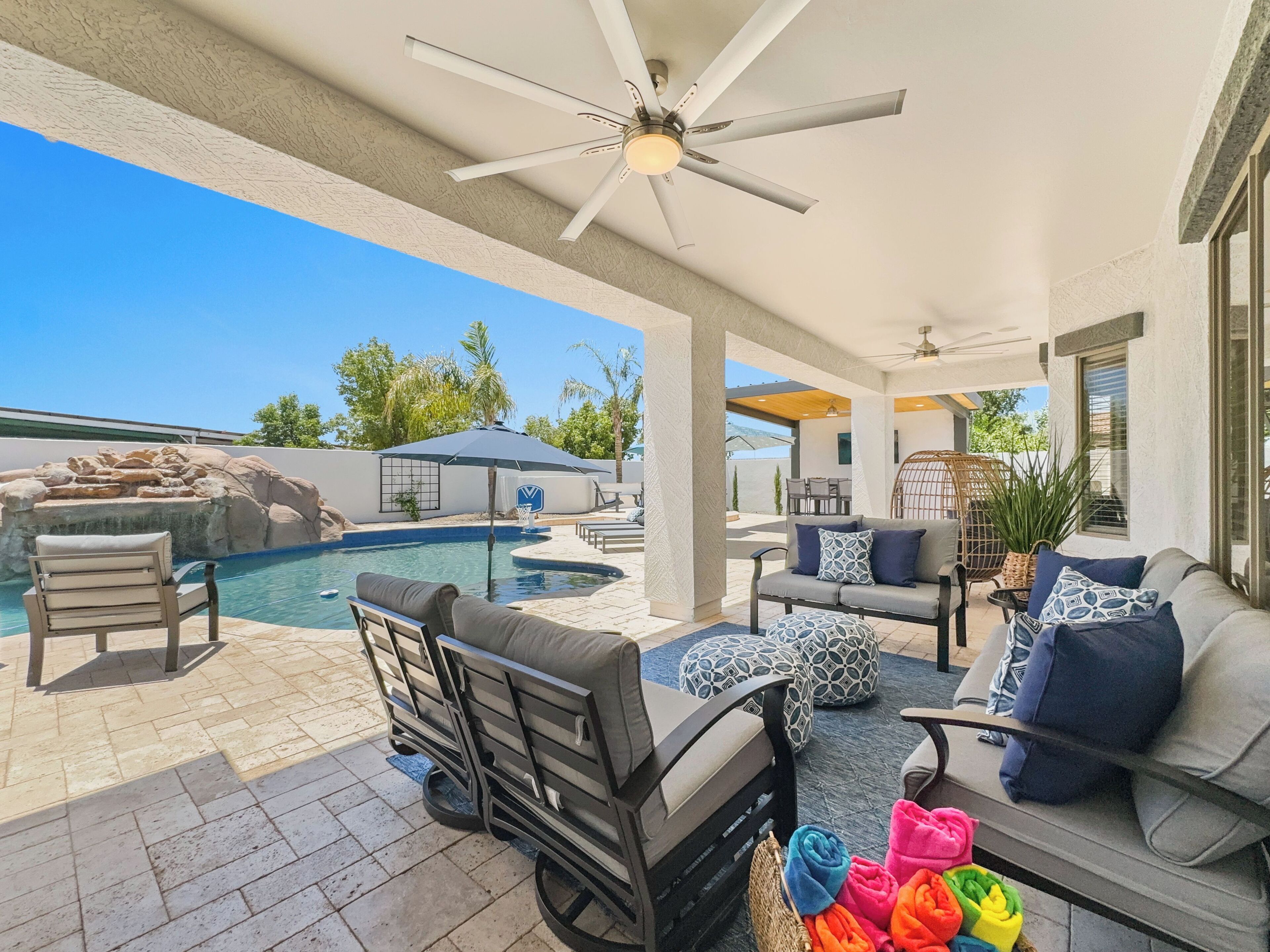 A poolside area with a ceiling fan, outdoor furniture, and a view of the pool.