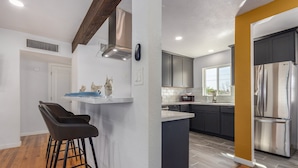 A modern kitchen with dark cabinets, a stainless steel refrigerator, and a bar area with stools. - 14th Coronado Historic District Phoenix (Phoenix)